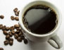 A cup of coffee with some coffee beans on the side